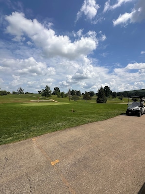 A golf course with a clear sky, green grass, and a golf cart. - Conestoga Covered Wagon on Working Farm - Willowmere (Fredericktown)