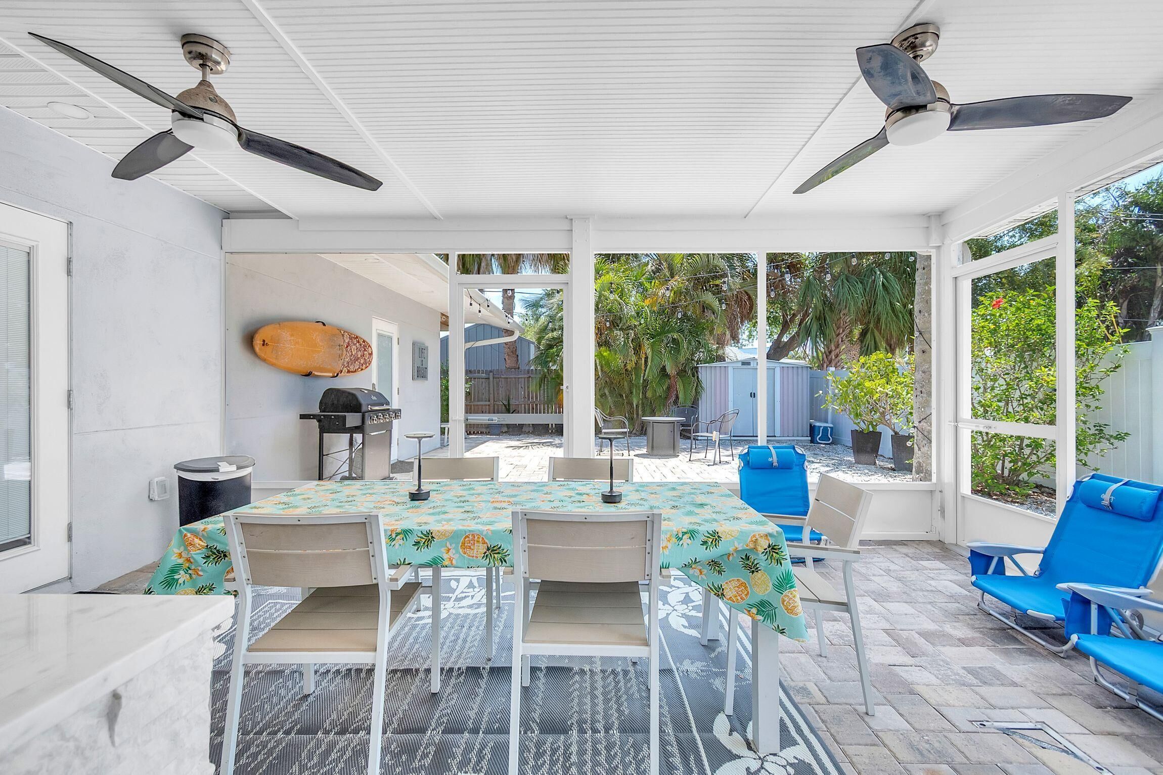 A covered patio with a table and chairs, ceiling fans, and a view of the backyard.