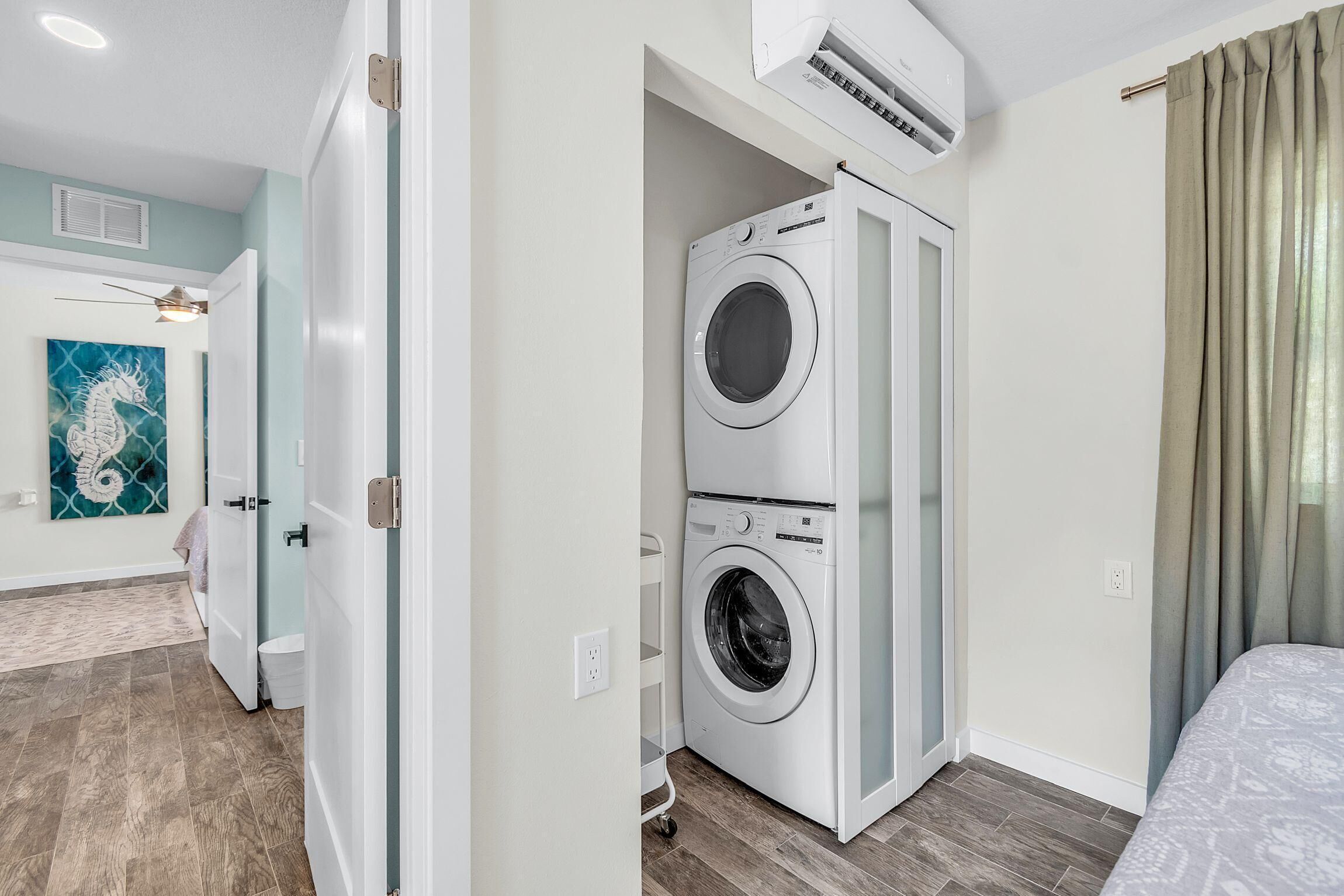 Ein Zimmer mit Wandwaschmaschine und Wandtrockner, einem Deckenventilator und einem Bild an der Wand.