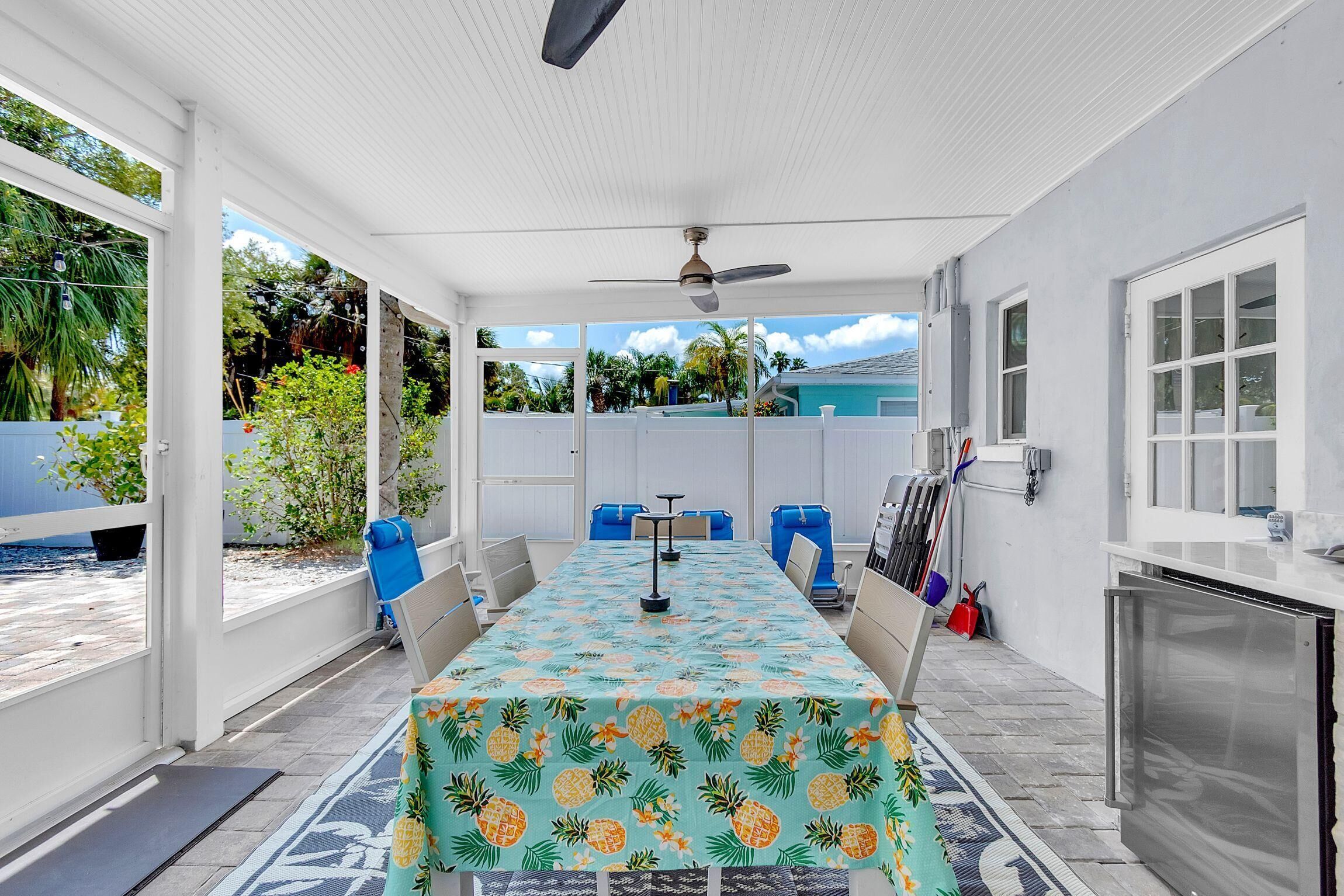 A covered patio with a table, chairs, a ceiling fan, and a view of the ocean.