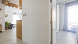 Interior moderno com parede de destaque em madeira, uma porta branca e vista para uma varanda.