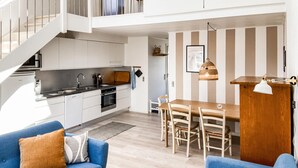 A modern kitchen with white cabinets, a dining area with a wooden table and chairs, and a staircase leading to an upper level. - Beautiful home in Vestervig with sauna (Vestervig)