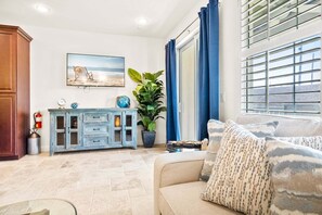 A living room with a sofa, a cabinet, a painting, and a window with curtains. - Cape Crossing 104 (Merritt Island)
