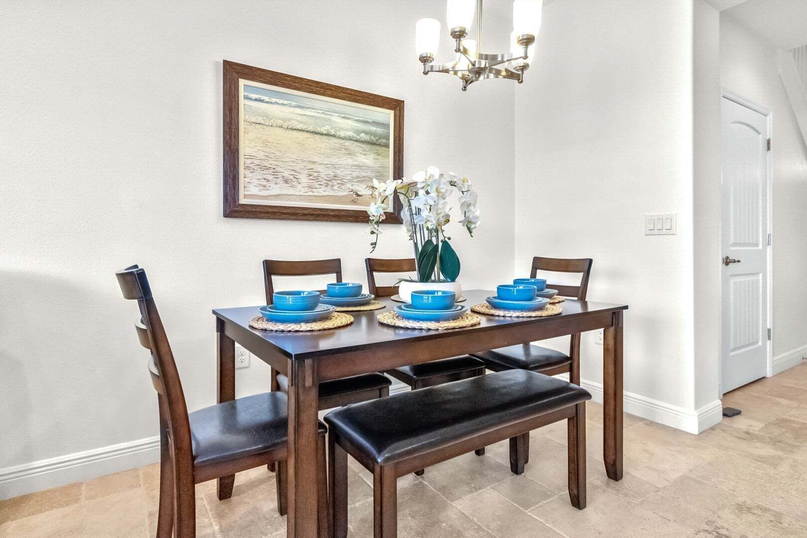 Comedor con mesa de madera, platos azules y una araña.