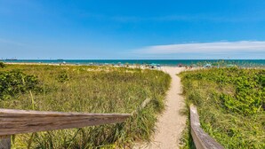 Ein Küstenpfad, der zum Meer führt, mit einem Holzgeländer.