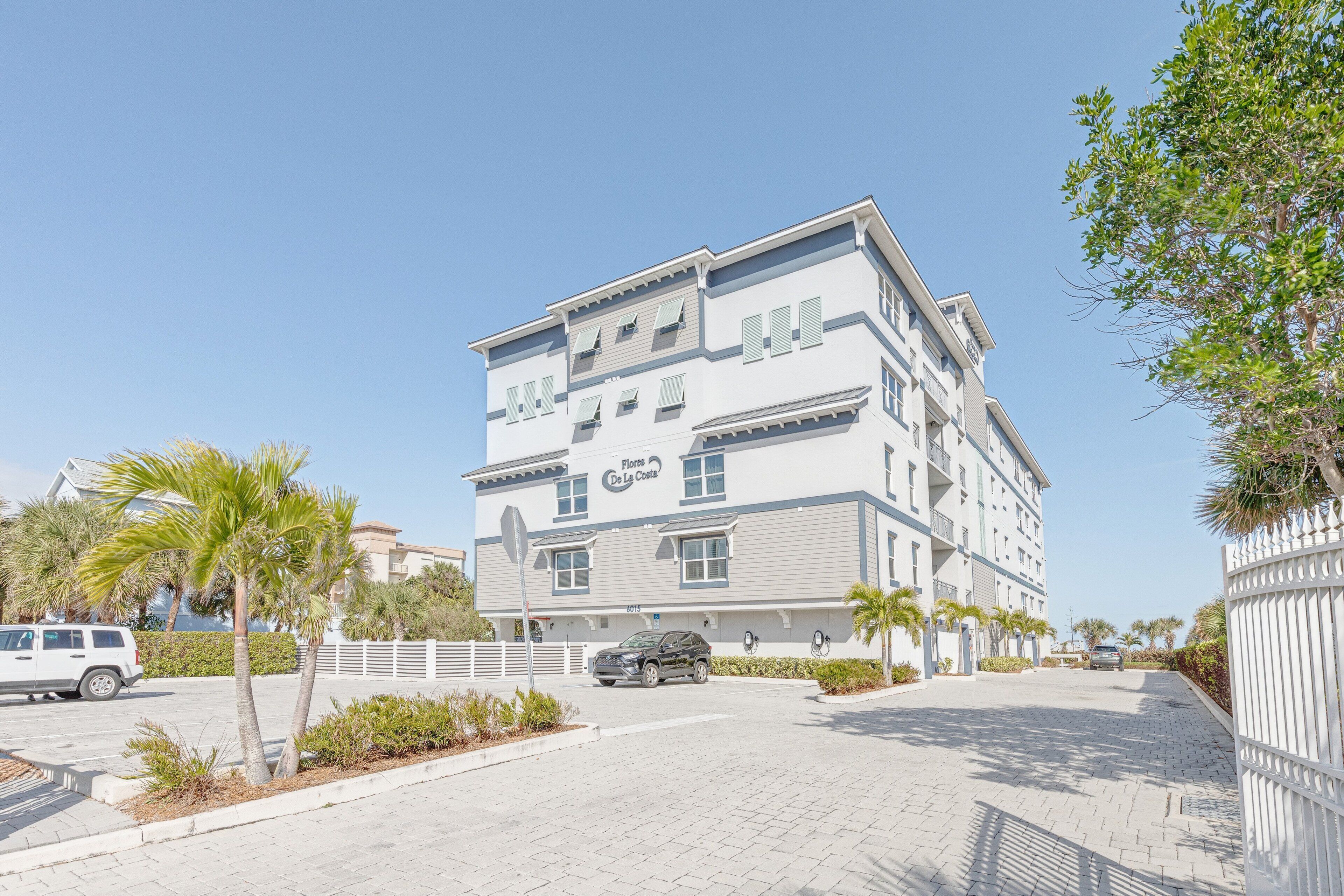 Een hotel met meerdere verdiepingen, een moderne gevel, een parkeerplaats en palmbomen.