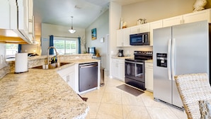 A modern kitchen with granite countertops, stainless steel appliances, and a dishwasher. - 620 S Easy St (Sebastian)