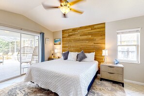 Ein Schlafzimmer mit einem Bett, einem Holzkopfende, einem Deckenventilator, einem Nachttisch und einem Fenster.