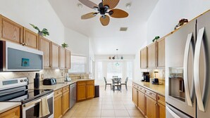 A modern kitchen with wooden cabinets, stainless steel appliances, and a ceiling fan. - Sebastian Serenity (Sebastian)