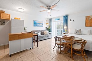 A compact living space with a kitchenette, a dining area, a sofa, and a bed. - The Plaza 227 (Cape Canaveral)
