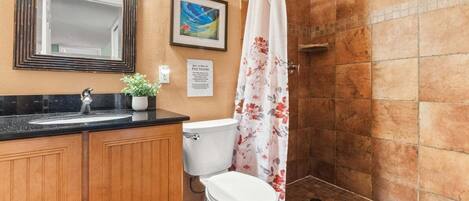 Une salle de bain équipée d’une douche, de toilettes, d’un lavabo et d’un miroir.