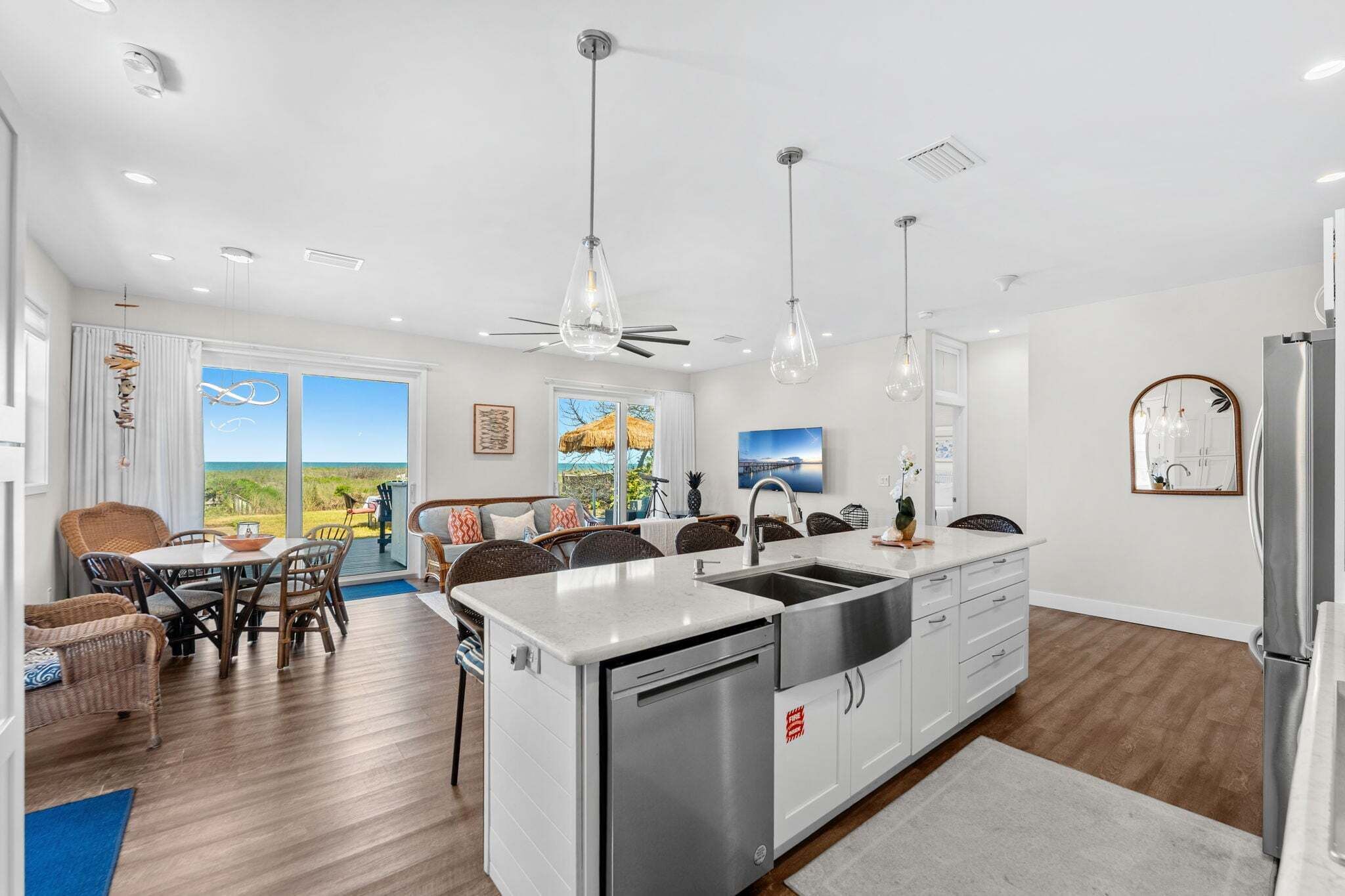A modern kitchen with a dishwasher, a sink, and a refrigerator. There is a dining area with chairs and a table.
