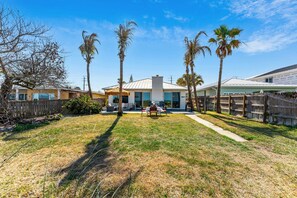 A residential property with a fenced backyard, a patio with outdoor furniture, and palm trees. - 659 S Atlantic Ave (Cocoa Beach)