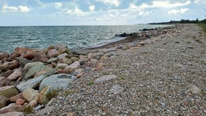 En stenet kystlinje med en stenstrand og krystalklart hav.