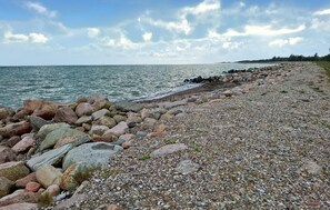Eine felsige Küstenlinie mit einem Kiesstrand und freiem Blick auf das Meer.
