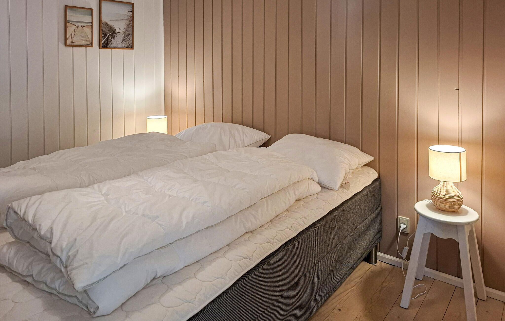 A bed with a headboard, a bedside lamp, and a wall with vertical paneling.