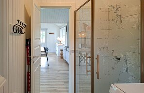 Ein Flur mit einer Treppe, die zu einem Essbereich führt, einer Glastür mit Griff und einer Wandleuchte.
