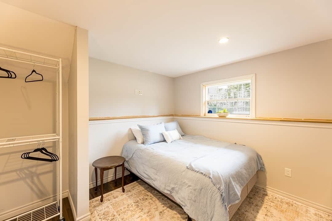 A bedroom with a bed, a small round table, a window with a view, and a closet with hangers.