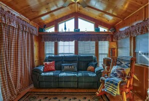 Een gezellig cabin interieur met een leren bank, geruite gordijnen en een houten plafond.