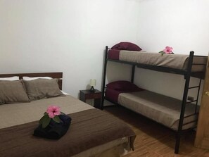Una habitación con una cama individual, una litera, una mesita de noche y una pequeña mesa.
