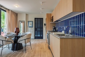 Eine moderne Küche mit Essbereich, Holzschränken und einer blau gefliesten Spritzschutzwand.