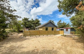 A single-story building with a fenced yard, surrounded by trees. - 3 bedroom nice home in Ringkøbing (Ringkøbing)