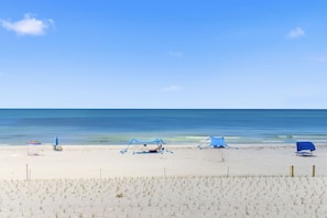 Ein Strand mit sandigem Vordergrund, blauem Himmel und ruhiger See.