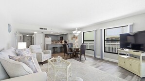 A modern living room with a sofa, chairs, a dining table, and a TV. - Amazing 1 bedroom with Gulf Views and Wraparound Balcony (Indian Shores)