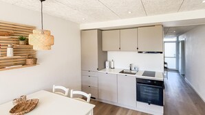 Een moderne keuken met een eetgedeelte, een wand van houten latten en een hangende lamp.