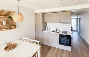 Eine moderne Küche mit Essbereich, einer Wand aus Holzleisten und einer Pendelleuchte.