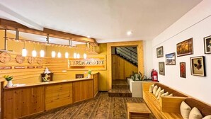A reception area with a wooden counter, a staircase, and a wall with framed pictures. - 3 Arch Resort - Ella (Ella)
