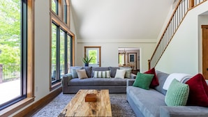 Un salon spacieux avec un grand canapé gris, une table basse en bois et une vue sur un balcon.