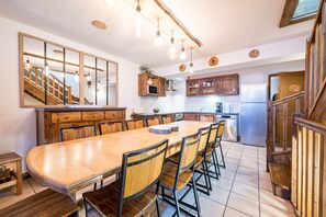Eine geräumige Küche mit einem großen Holztisch, mehreren Stühlen und einem eingebauten Backofen.