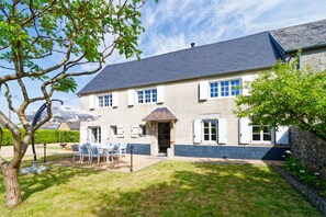 A two-story house with a sloped roof, a front porch with chairs, and a well-maintained lawn. - La Maison de Gianni - 7km de la Plage (Quettreville-sur-Sienne)