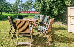 A wooden outdoor table and chairs set on a grassy lawn with trees in the background. - 3 bedroom gorgeous home in Holstebro (Holstebro)