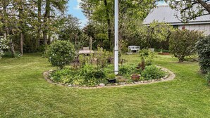 A well-maintained garden with a central circular flower bed, a tall metal pole, and a white bench in the background. - Stunning apartment in Holstebro with WiFi (Holstebro)