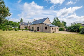 A stone house with a sloped roof, a large grassy yard, and a clear blue sky. - La Cidrerie - Havre de paix breton (Surzur)