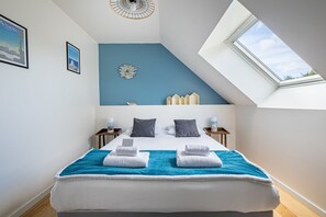 A bedroom with a skylight, a bed with white linens, a blue accent wall, and a decorative wall piece. - La Cidrerie - Havre de paix breton (Surzur)