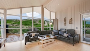 A spacious living room with a large window, a leather sofa, a wooden coffee table, and a view of the outdoors. - "Mine" -  from the sea by Interhome (Hvide Sande)