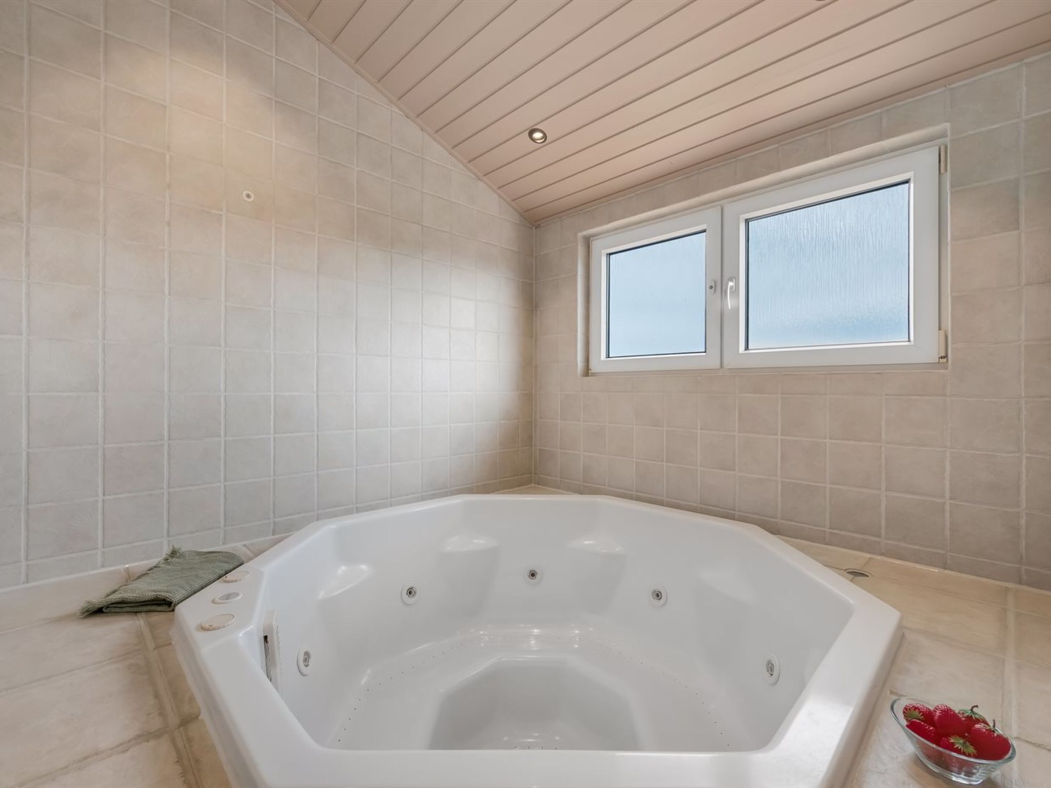 Une salle de bain moderne avec une baignoire sur pieds, une fenêtre et un bol de fraises posé sur le sol.