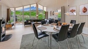 A modern interior with a dining area, sofa, and large windows offering a view of the outdoors. - "Mine" -  from the sea by Interhome (Hvide Sande)
