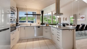 A modern kitchen with a large island, white cabinetry, and a view of the outdoors. - "Mine" -  from the sea by Interhome (Hvide Sande)