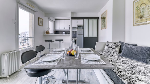 A modern kitchen with a dining area, a sofa, and a radiator. - Le Saint-Denis Pleyel - À 10 min de Paris en métro (Saint Denis)