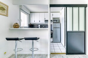 Eine moderne Küche mit weißen Schränken, einem Edelstahl-Kühlschrank und einer Bar mit Barhocker.