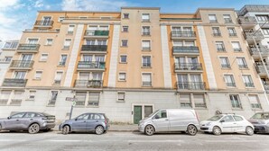 A multi-story residential building with balconies, a street sign, and parked cars. - Le Saint-Denis Pleyel -  À 10 min de Paris en métro (Saint Denis)