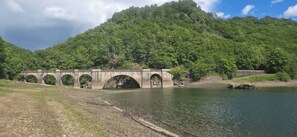 Un pont de pierre enjambant une riviĂšre paisible, entourĂ© dâune vĂ©gĂ©tation luxuriante et de collines.