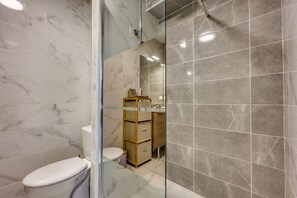 Ein Badezimmer mit Toilette, Dusche und Spiegel.