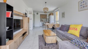 Ett modernt vardagsrum med en grå soffa, ett soffbord i trä och en bokhylla.