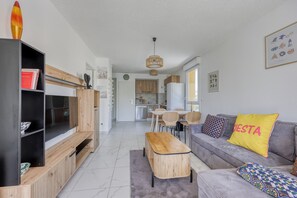 Ein modernes Wohnzimmer mit grauem Sofa, Holztisch und Bücherregal.