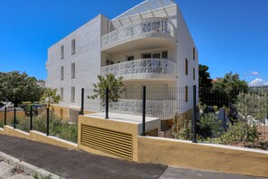 Ein modernes Gebäude mit weißer Fassade, mehreren Balkonen und einem verschlossenen Eingang.